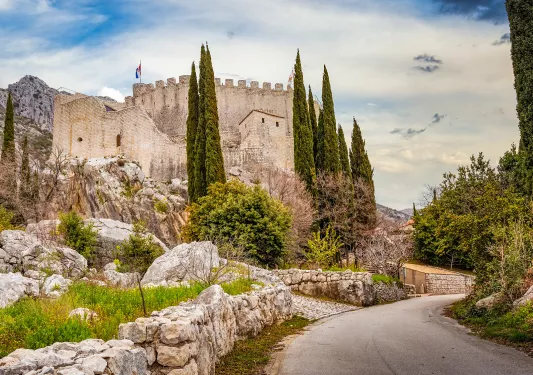 Shot of road leading to white brick castle structure. 