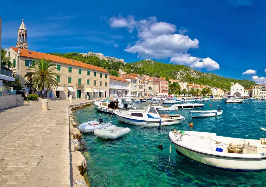 Wide shot of Croatian coastal town, boats, blue water, hills, etc.
