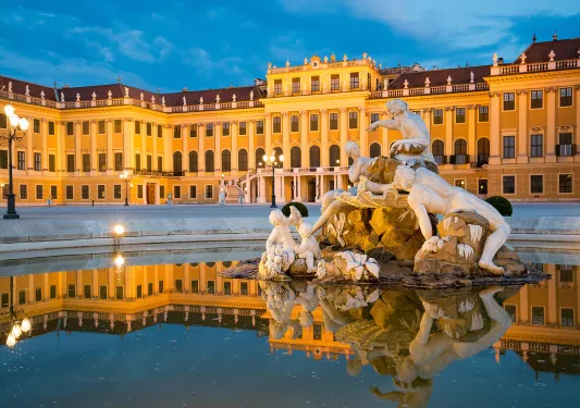 Ornate marble fountain with statues of Greek gods and figures at night.