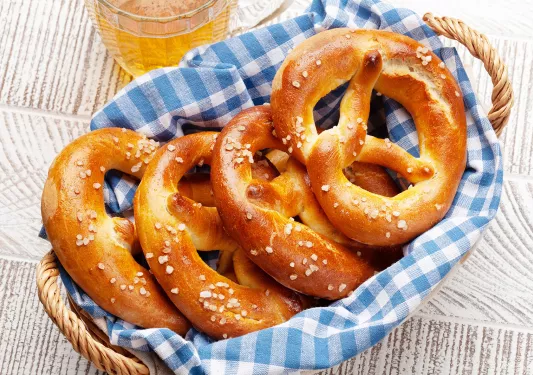 Lager beer mug and fresh baked homemade pretzel with sea salt on wooden table. Classic beer snack