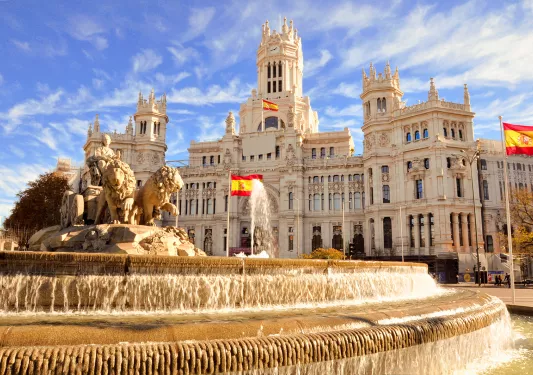 Shot of the Plaza de Cibeles, Spanish flags flying around it.