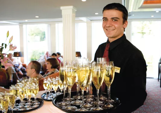 Waiter holding tray of sparkling white wine.