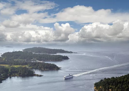 Boat traveling between islands - big white puffy clouds in a blue sky