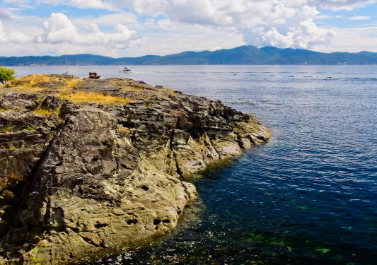 Bench at the shore, public Ruckle Provincial Park shoreline on the Salt Spring Island, largest of the Gulf Islands in British Columbia