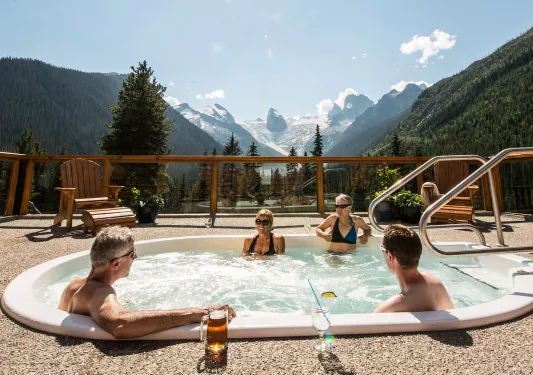 Four guests in hot-tub, mountainous vista behind them.