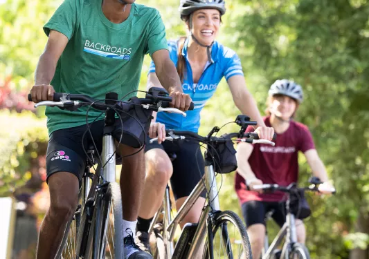 Three guests biking towards camera, all smiling.