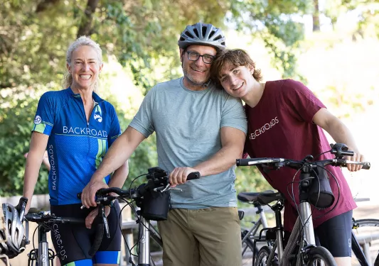 Three guests with bikes and gear, all smiling at camera.