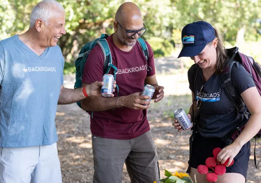 Three guests around lunch table, beers in hand.