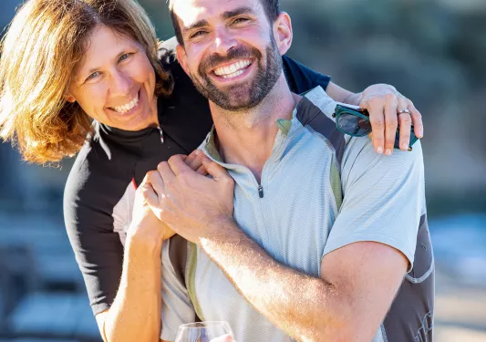 Two guests embracing, one holding glass of beer.