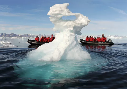Riding in a zodiac boat past a large iceberg
