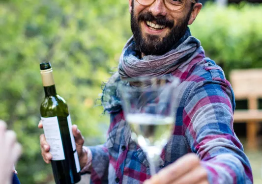 Local with wine bottle, handing you a glass.