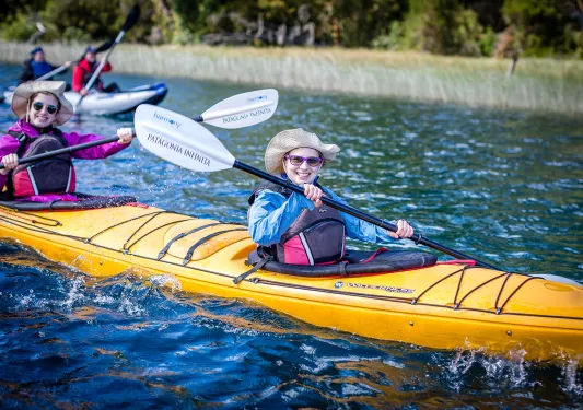 Four guests in kayaks, smiling at camera.