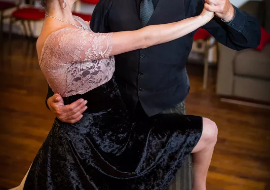 Two folks at dance class, dressed in black dancing clothes.