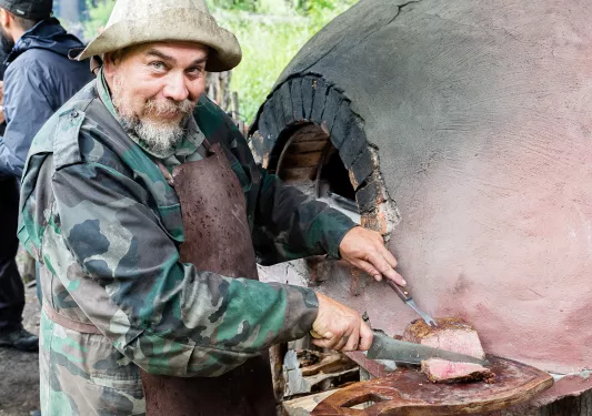 Local cutting meat, brick/clay oven behind them.