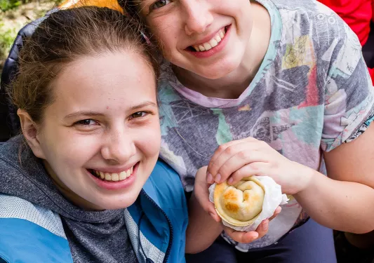 Two young guests smiling at camera, pastries in hand.