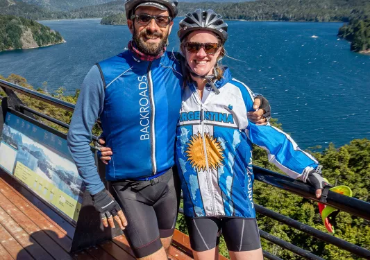 Two guests on bridge, overlooking lake, mountains.