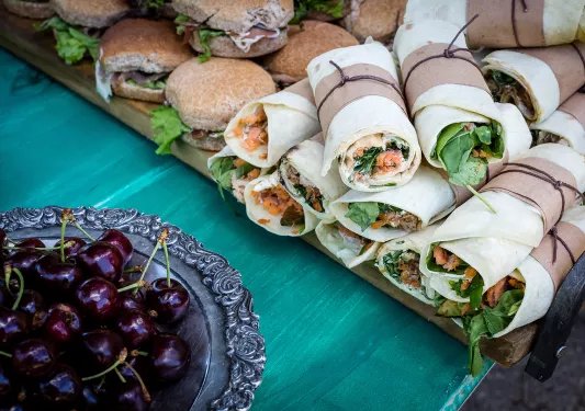 Platter of sandwiches and wraps, cherries.