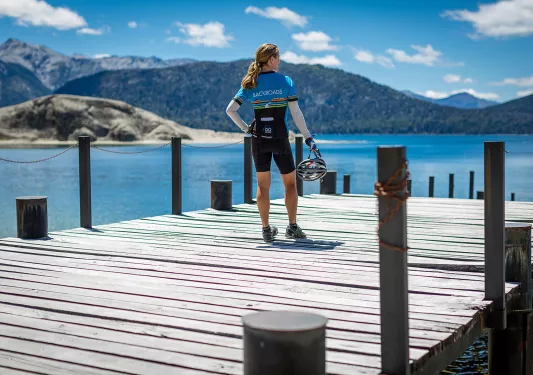 Guest in bike gear on pier, overlooking mountains, lake.