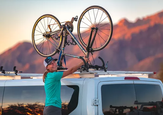 Guide smiling at camera mounting bike on van in arizona