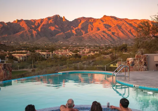 Guests in hot tub at sunset facing mountains AZ