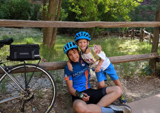 Two young guests in bike gear leaning on fence, bike beside them.