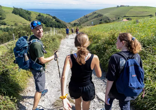 Group of guests walking towards French coast, large hills on either side.