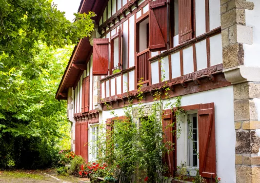Housefront shot of red and white cottage among forest.