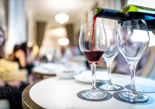 Close-up of hand pouring red wine.