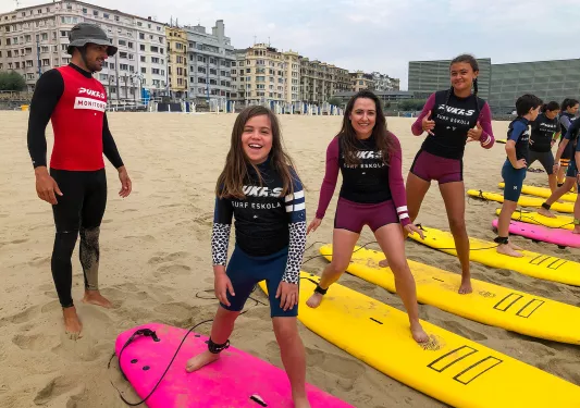 Group of young guests at surf lesson, instructor behind them.