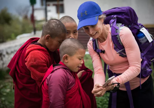 Woman showing her phone to young monks in Bhutan
