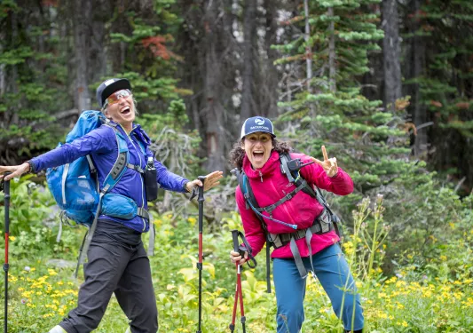 Two guests in hiking gear, posing for camera among forest.