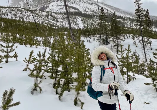 Guest hiking in snow shoes, large mountain in background.