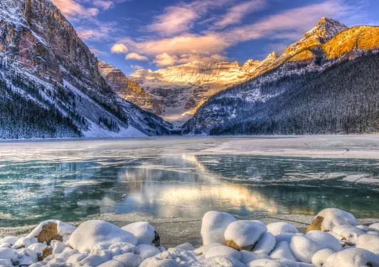 Wide shot of frozen lakebed, mountains, sunset.
