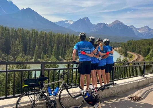 Four guests looking towards forest and mountains, bikes beside them.