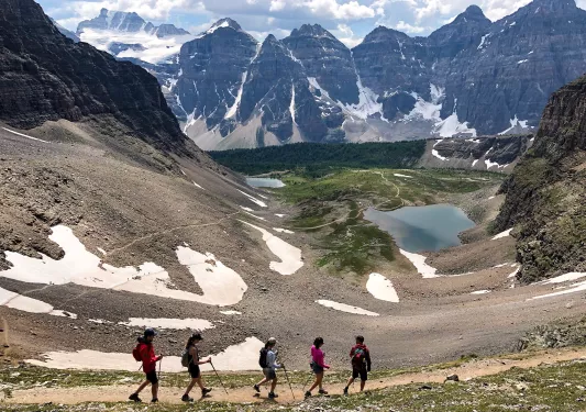 Five guests walking on gravel mountainside.