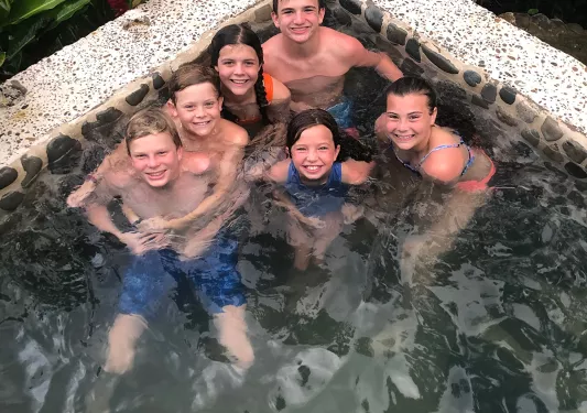 Six young guests in hot tub, looking up at camera.