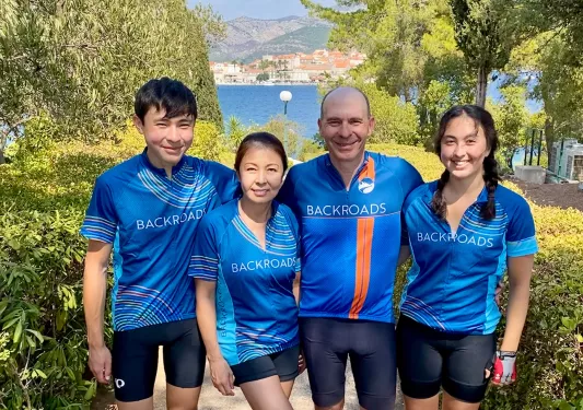 Four guests on staircase, trees, ocean behind them.