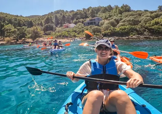 Group of guests starting to kayak, coast behind them.