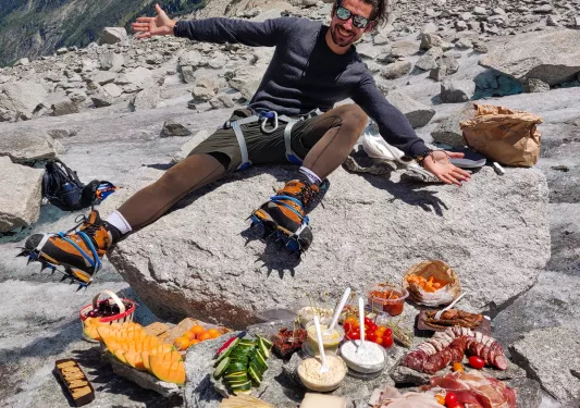 Leader overlooking lunch spread on rocks, cliffside behind them.