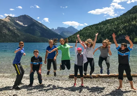 Young Backroads guests posing for a picture in front of mountains and lake