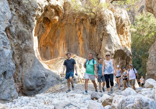 Guests walking through craggy valley, cliffs on either side.