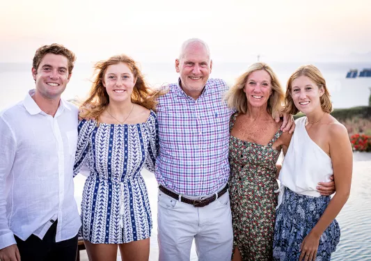 Group of guests posing for camera, sunset in background.