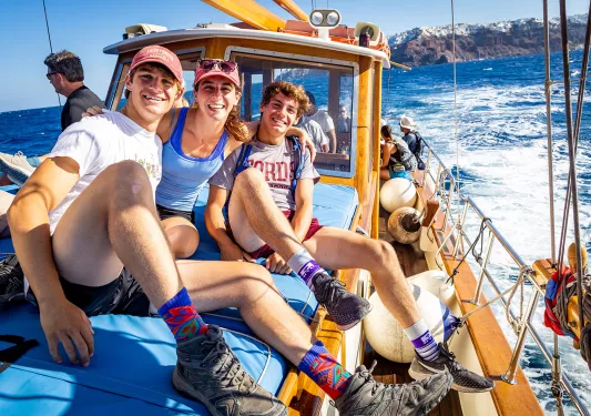 Group of guests on boat, three smiling at camera.