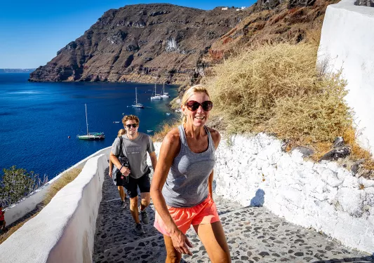 Group of guests walking up stone stairs, ocean, cliffs behind them. 