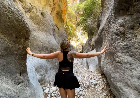 Guest in between large rock cliffs. Hands on each of them.