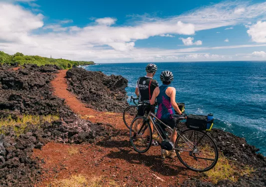 Two bikers taking a break and looking out at the ocean in Hawaii