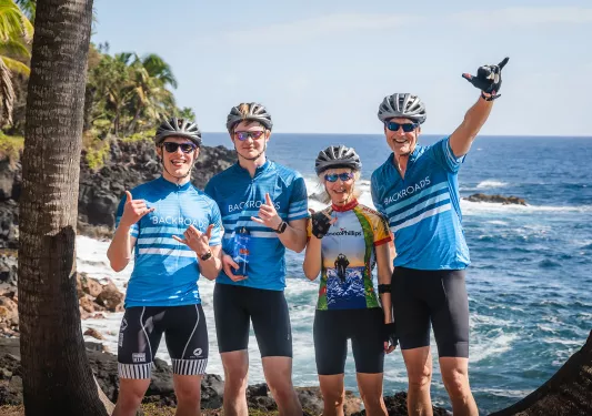 Guests posing under a palm tree by the coast in Hawaii