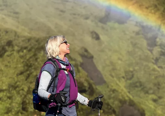 Hiker standing underneath a rainbow.