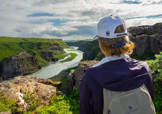 Guest overlooking green valley, river, cliffs.