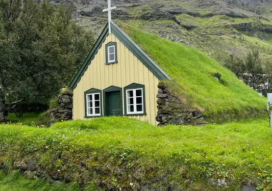 Small grass-roofed countryside church, overcast sky.